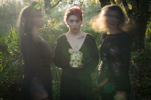 Ethereal forest scene with figures in black garments captured in natural lighting.