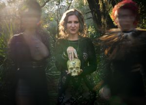 Dreamy woodland photography featuring dark-clothed figures in filtered sunlight.