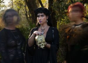 Atmospheric forest portrait showing figures in black against natural foliage and lighting.