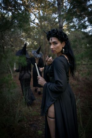 Dark forest photoshoot featuring gothic fashion and dramatic poses among trees.
