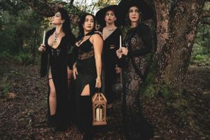 Atmospheric group photo in dark Victorian-inspired clothing against forest backdrop.