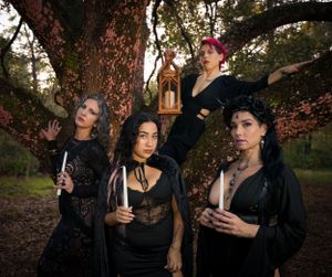 A mystical forest photoshoot featuring people in dark clothing gathered around a twisted tree trunk.