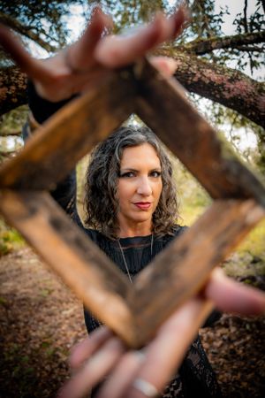 Artistic photo through an antique frame held up in a forest setting with autumn foliage.