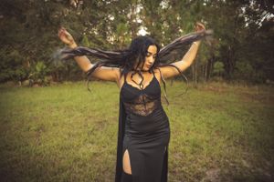 Dynamic poses in black gothic attire captured in an outdoor woodland setting.