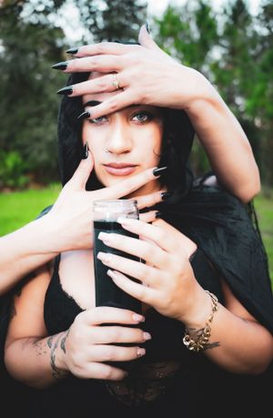 Ethereal portraits featuring dark nails and mystical poses in natural setting.