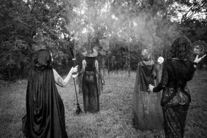 Black and white series of gothic figures in flowing robes amid a misty field.