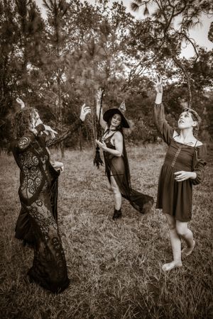 Black and white photos capturing mystical dancing figures in flowing dresses among trees.