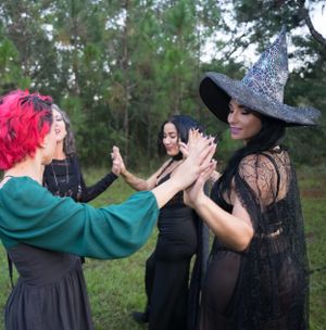 Group of people in gothic attire performing synchronized movements in a forest clearing.