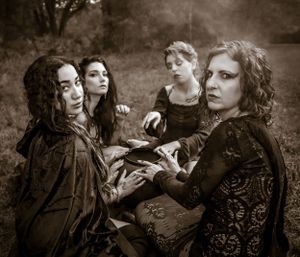 Vintage-style sepia photograph showing a gothic-themed gathering in elaborate dark clothing.