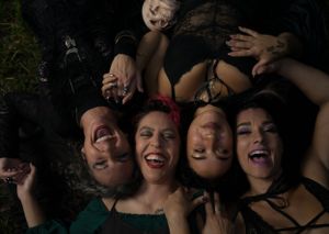 People lying down in a circle formation under dim lighting against a dark background.
