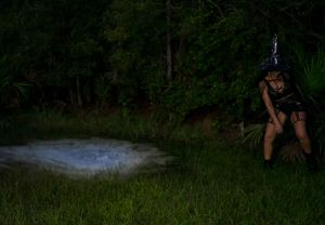 A nighttime outdoor scene showing figures gathered in a grassy area.