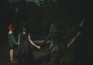 People holding hands in a circle formation outdoors at night on grass.