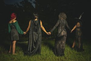 A group performing a ritual or ceremony outdoors at night while holding hands.