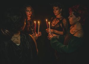 A row of people holding lit candles in darkness creating a warm glow.