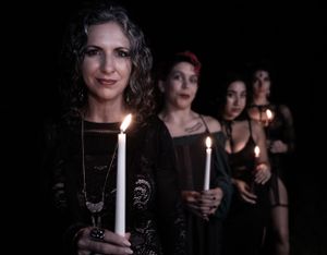 Several people stand together holding glowing white candles against a black background.