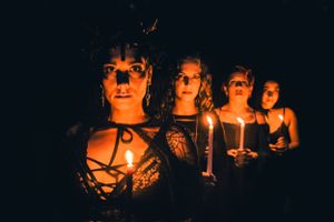 Candlelight illuminates faces in darkness creating an ethereal glow.