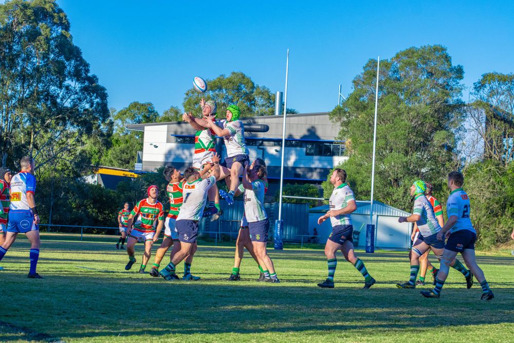Rugby players jumping for ball during lineout play in competitive match.