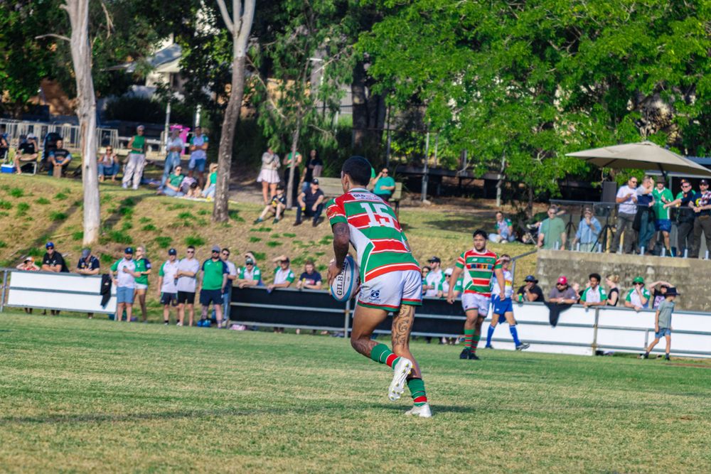 Rugby player executing a powerful kick during a match on a grass field.