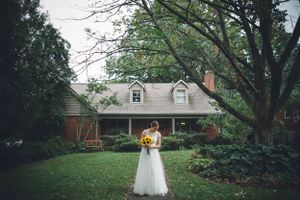 Woman in wedding dress stands in front of her house in Gunnison, Colorado.