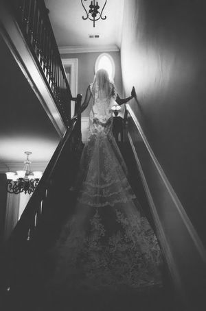 Bride walks up steps with her train following her.