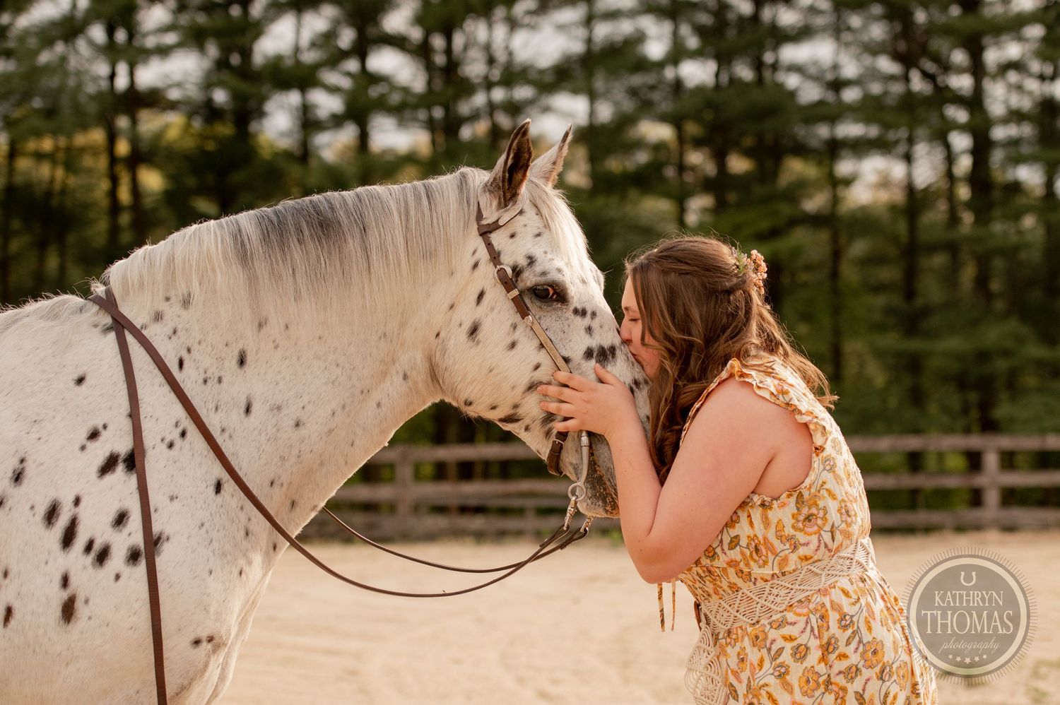 A tender moment shared with a spotted white horse in an outdoor arena setting.