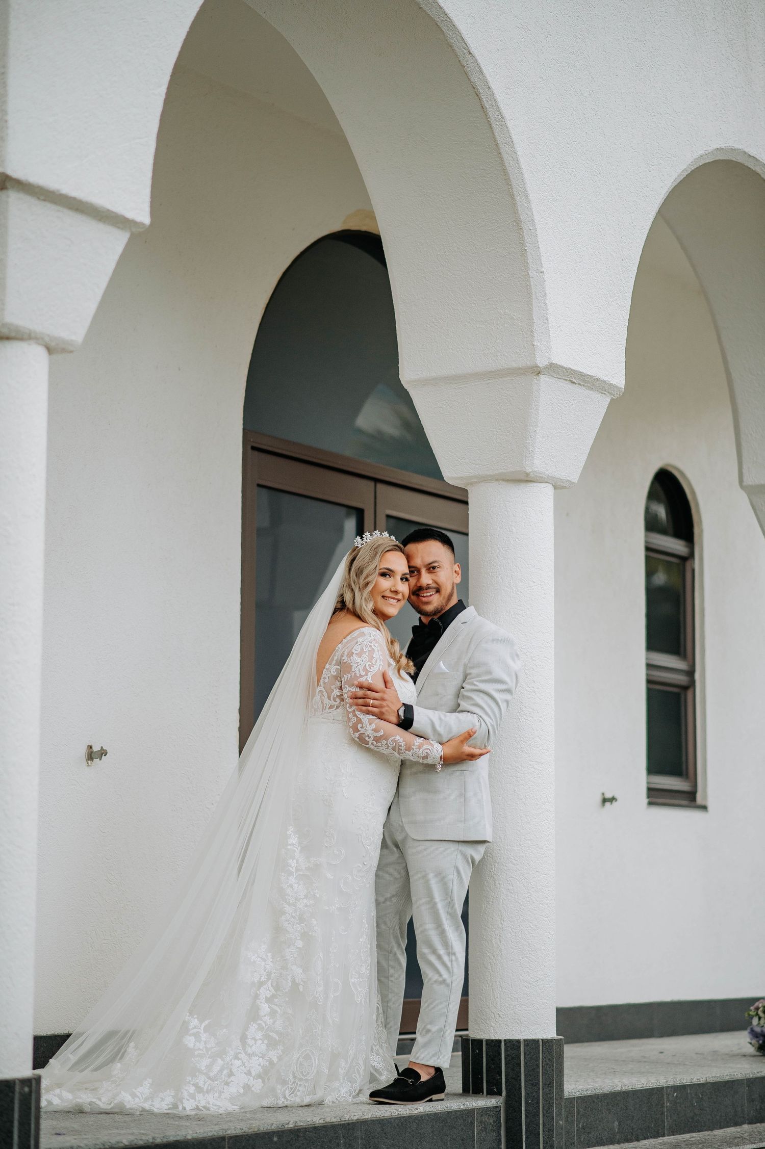 Romantic wedding portrait under white arched architectural details.