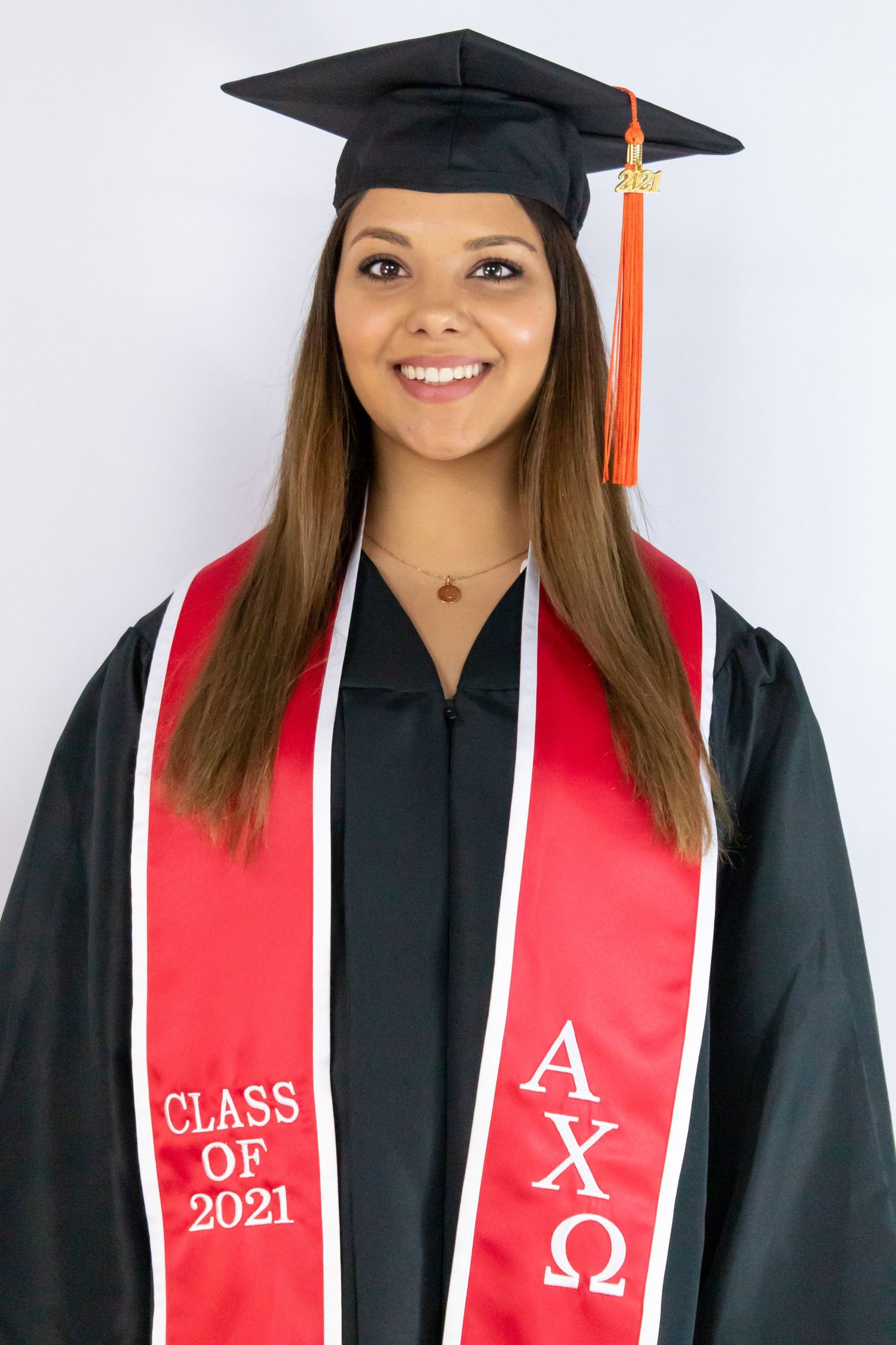Graduate in black cap and gown with red stole poses for commencement portrait.
