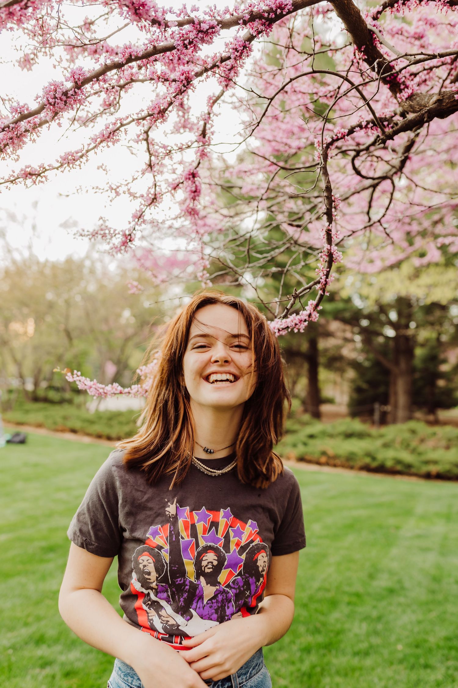 Cheerful springtime portrait under blooming cherry blossom trees on campus grounds.