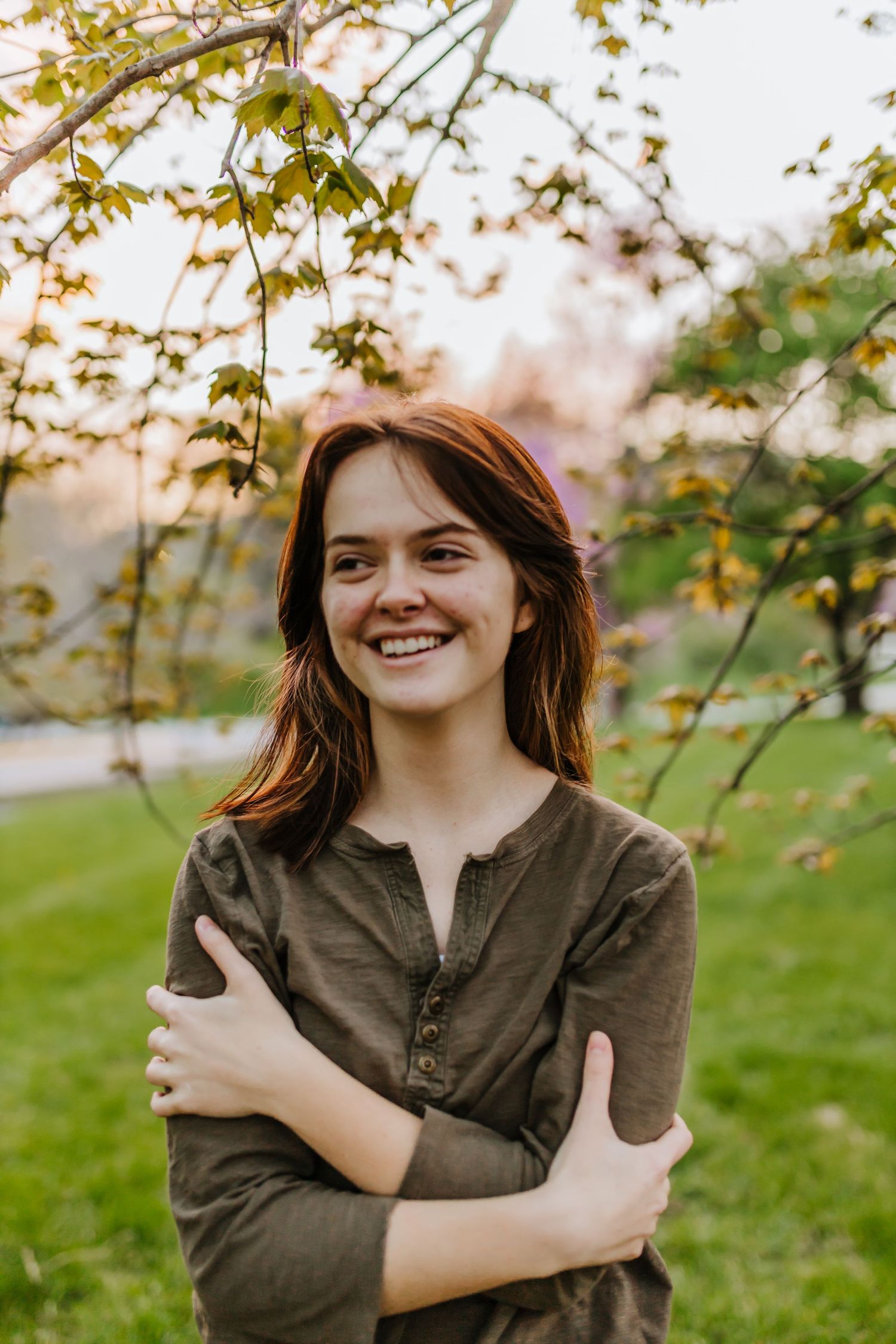 Casual outdoor portrait under autumn leaves in a natural campus setting.