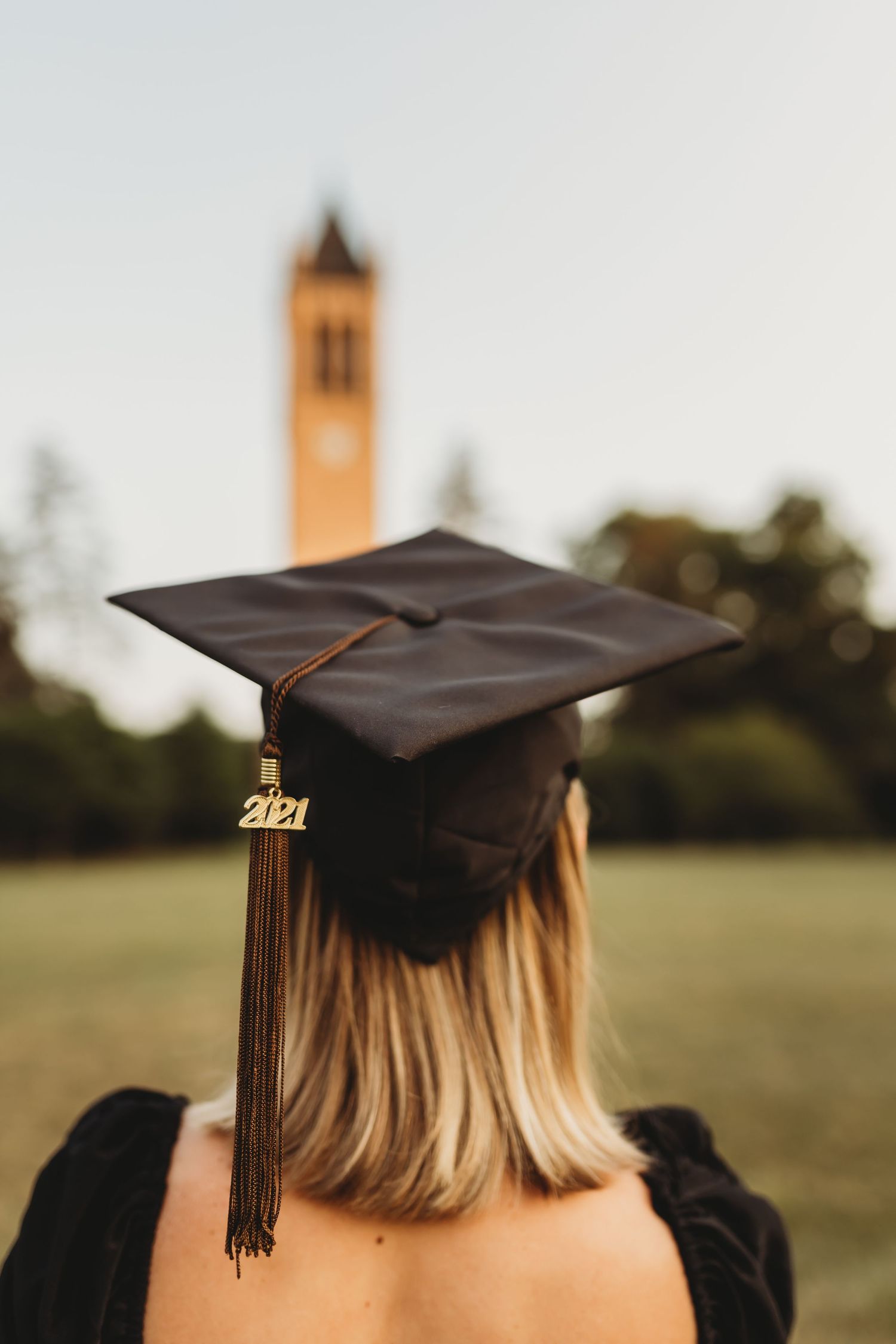 Graduation cap with 2021 tassel against blurred tower background.