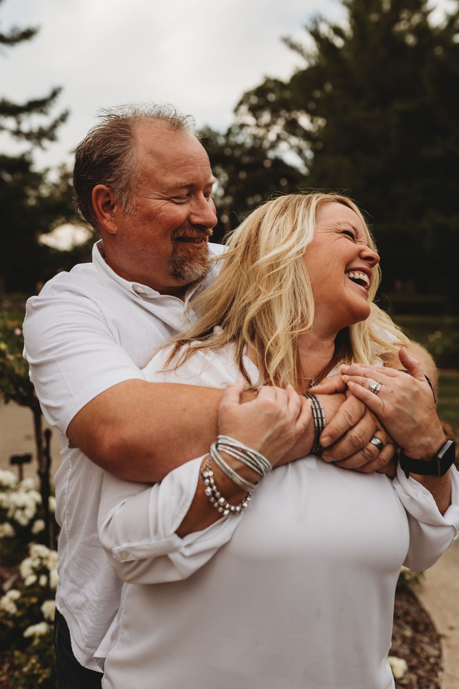 Joyful couple embracing and laughing together outdoors during sunset.
