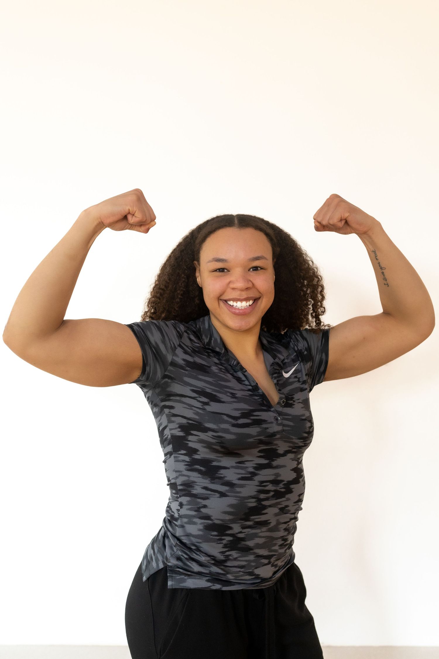 Athletic person in gray camo shirt flexing muscles against white background.