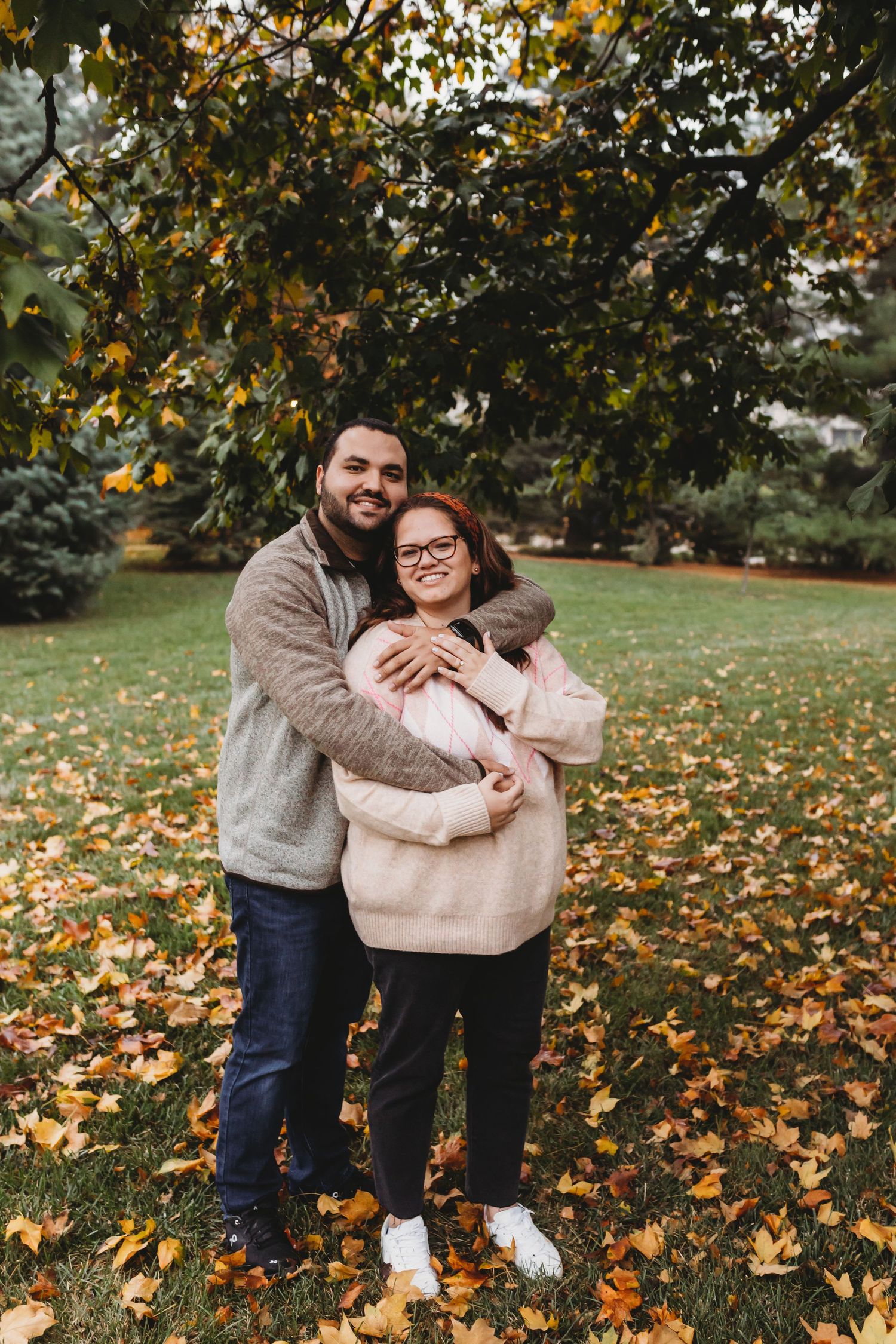 Couple embracing on autumn lawn covered with fallen leaves.