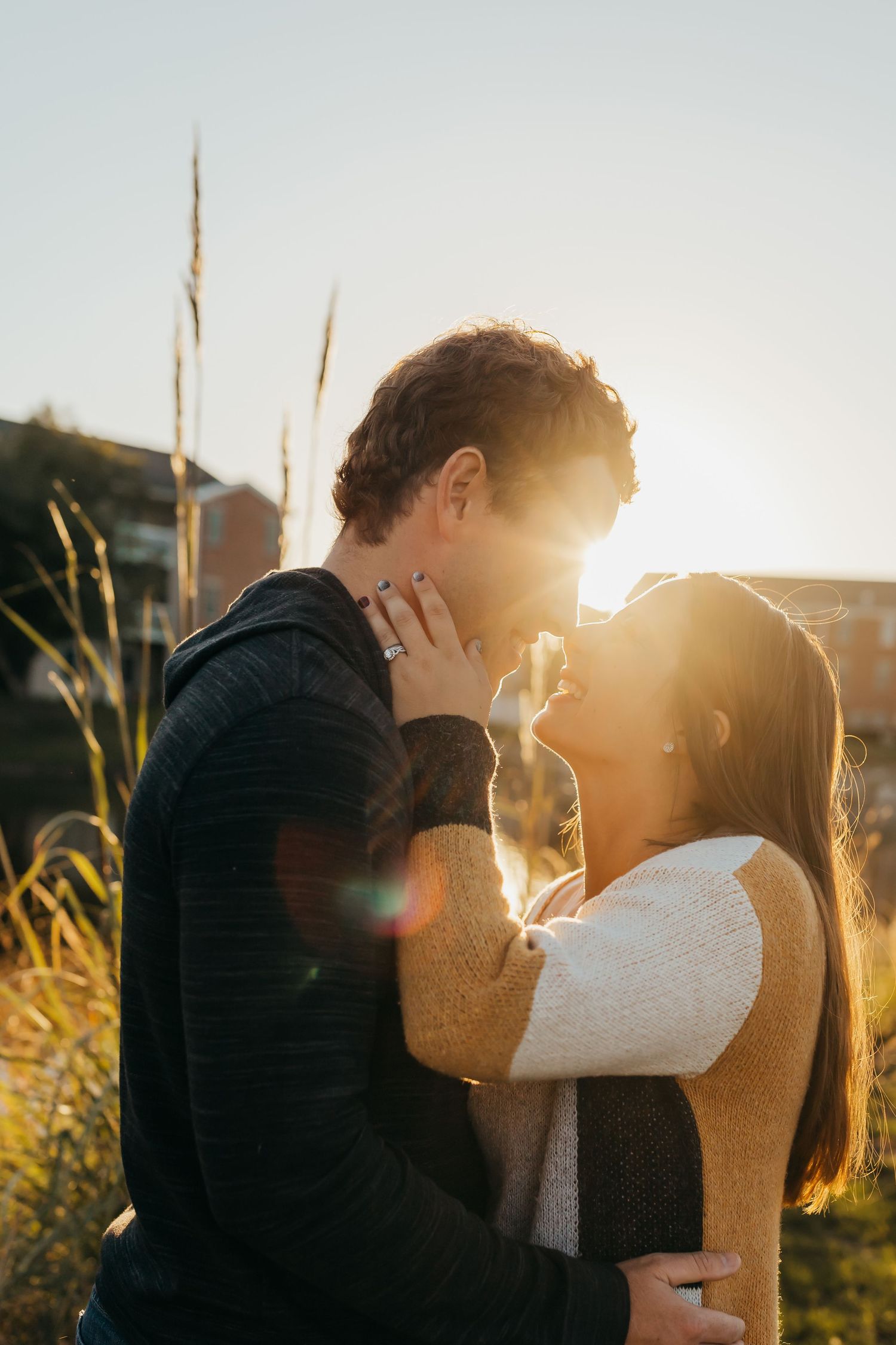 Silhouetted couple embracing in golden sunlight with tall grass.