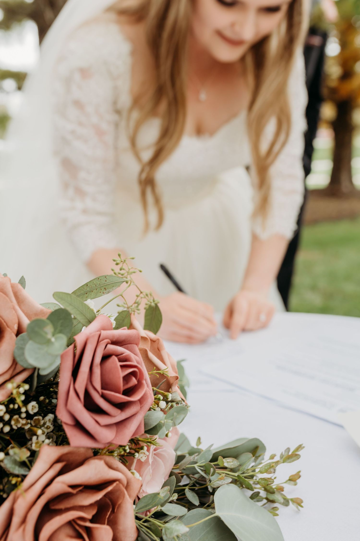 Close-up of dusty pink roses and wedding document signing.