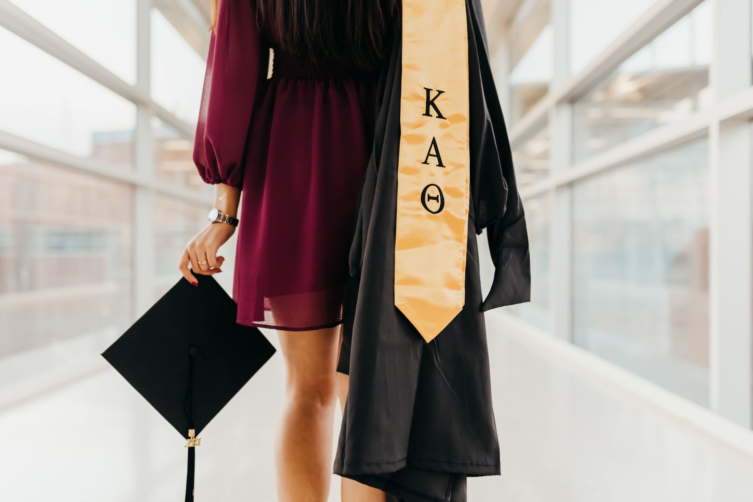 Graduation regalia including cap and KAO stole displayed in bright hallway.