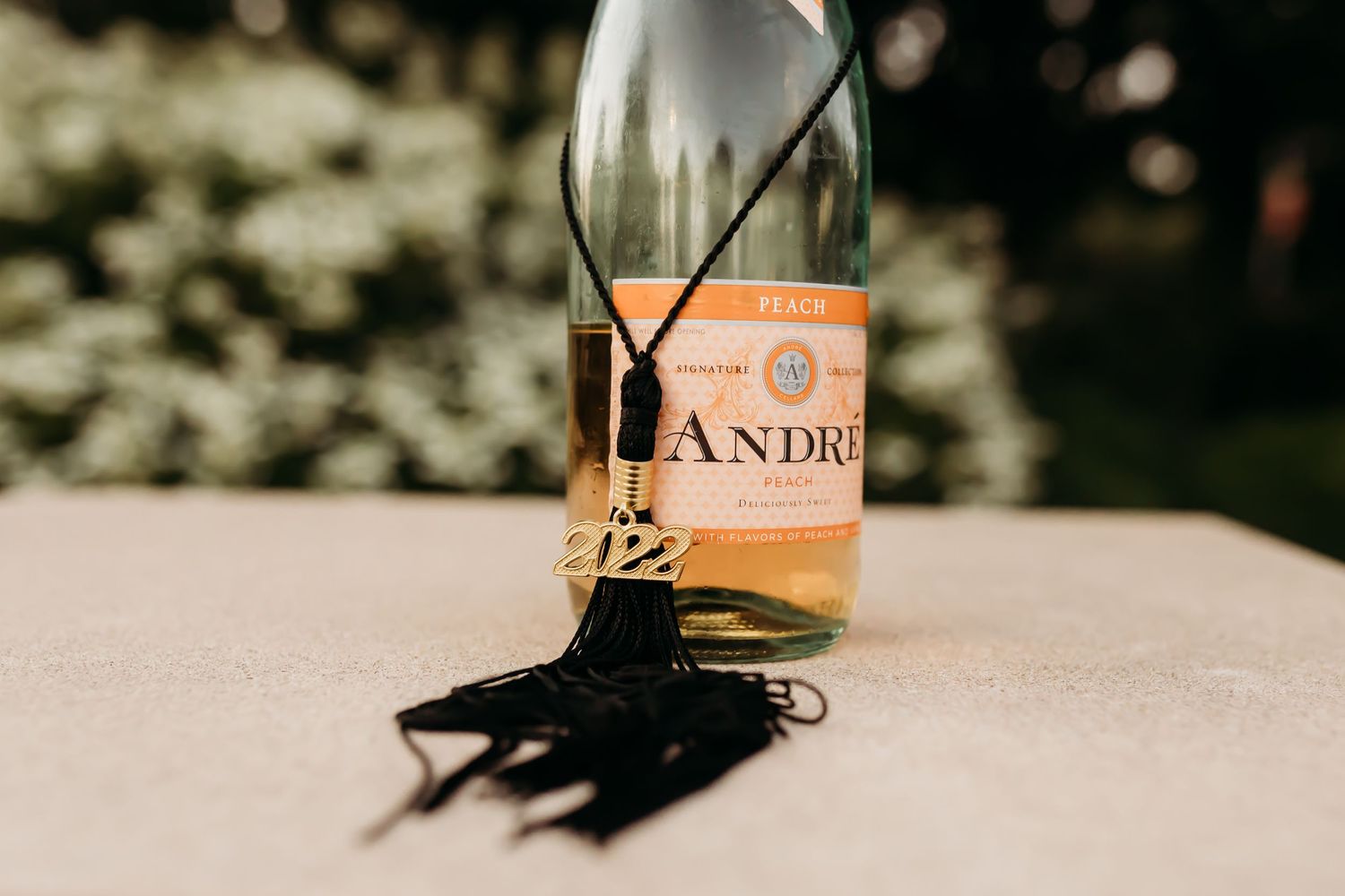 Graduation tassel and champagne bottle arranged together for celebratory photo.