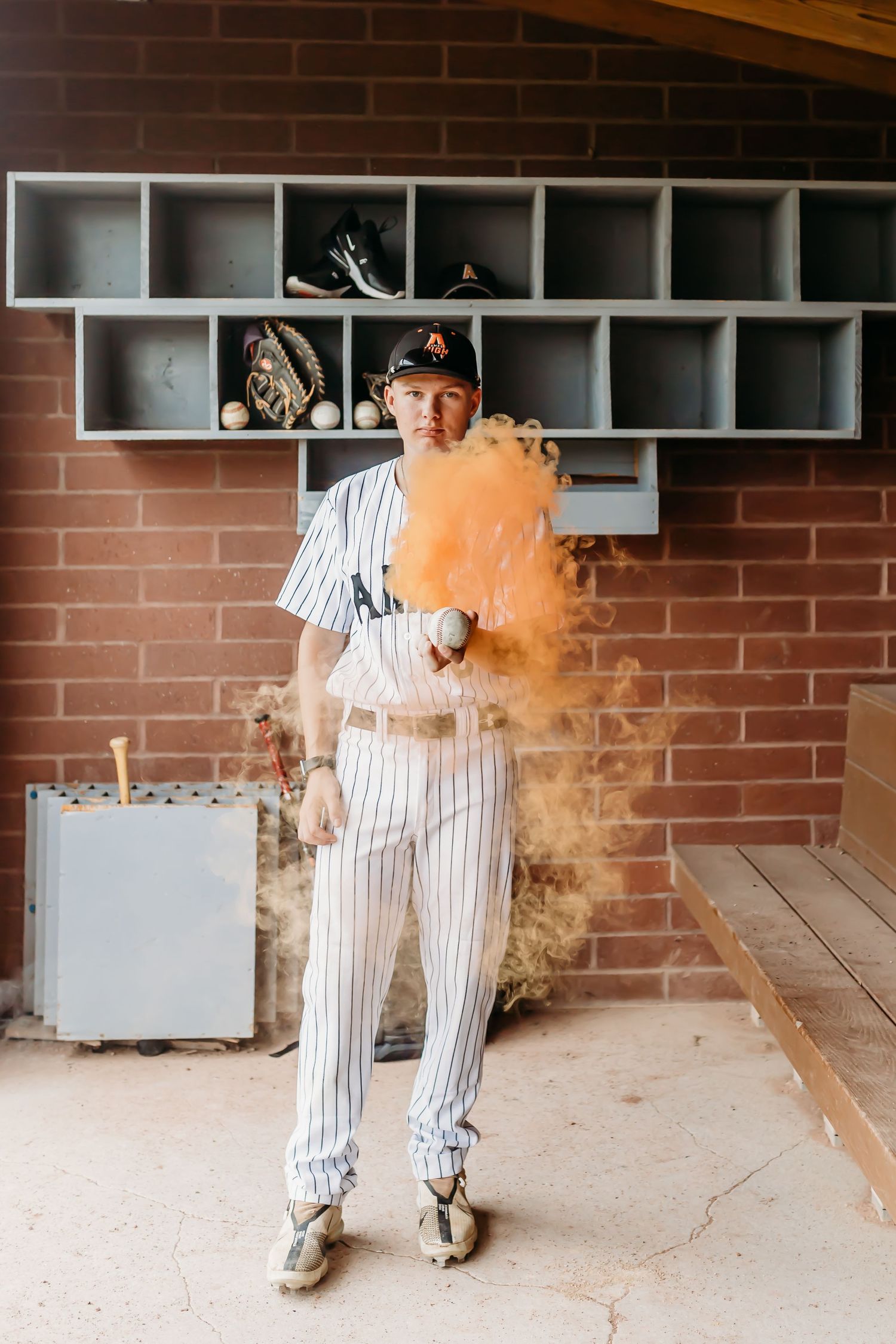 Baseball player in pinstripe uniform surrounded by orange smoke in dugout cubby setting.