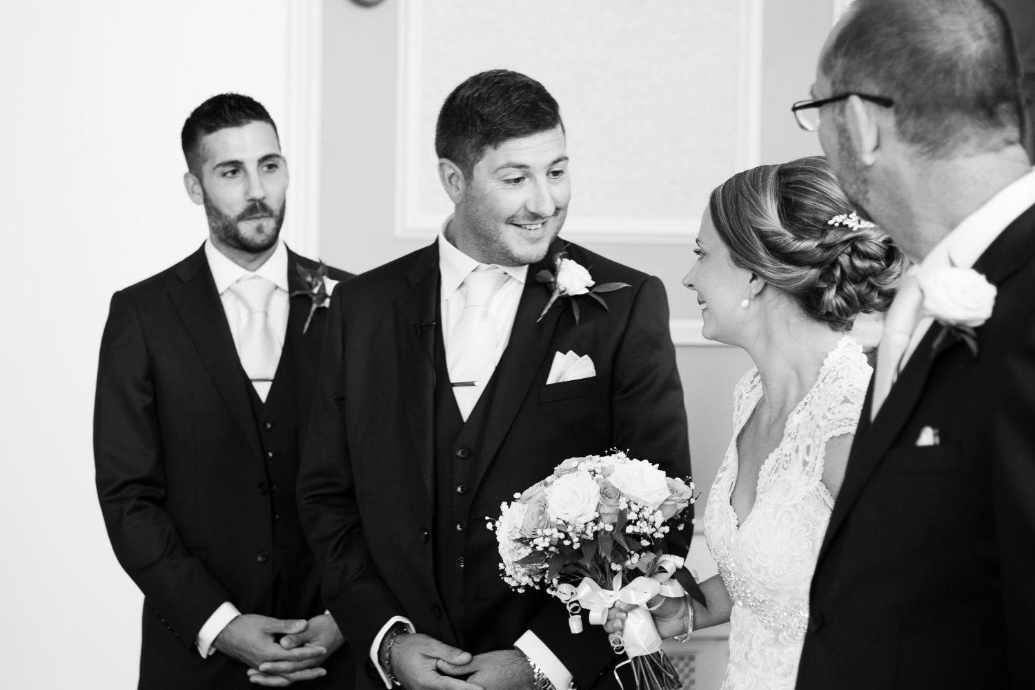 A black and white wedding ceremony moment with attendees gathered in formal attire.