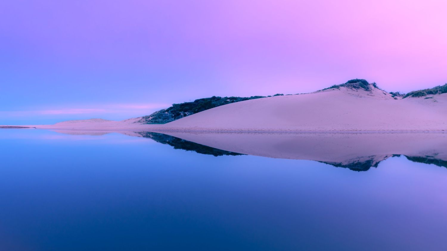 Ethereal purple and blue mountain landscape reflecting perfectly in still water at twilight.