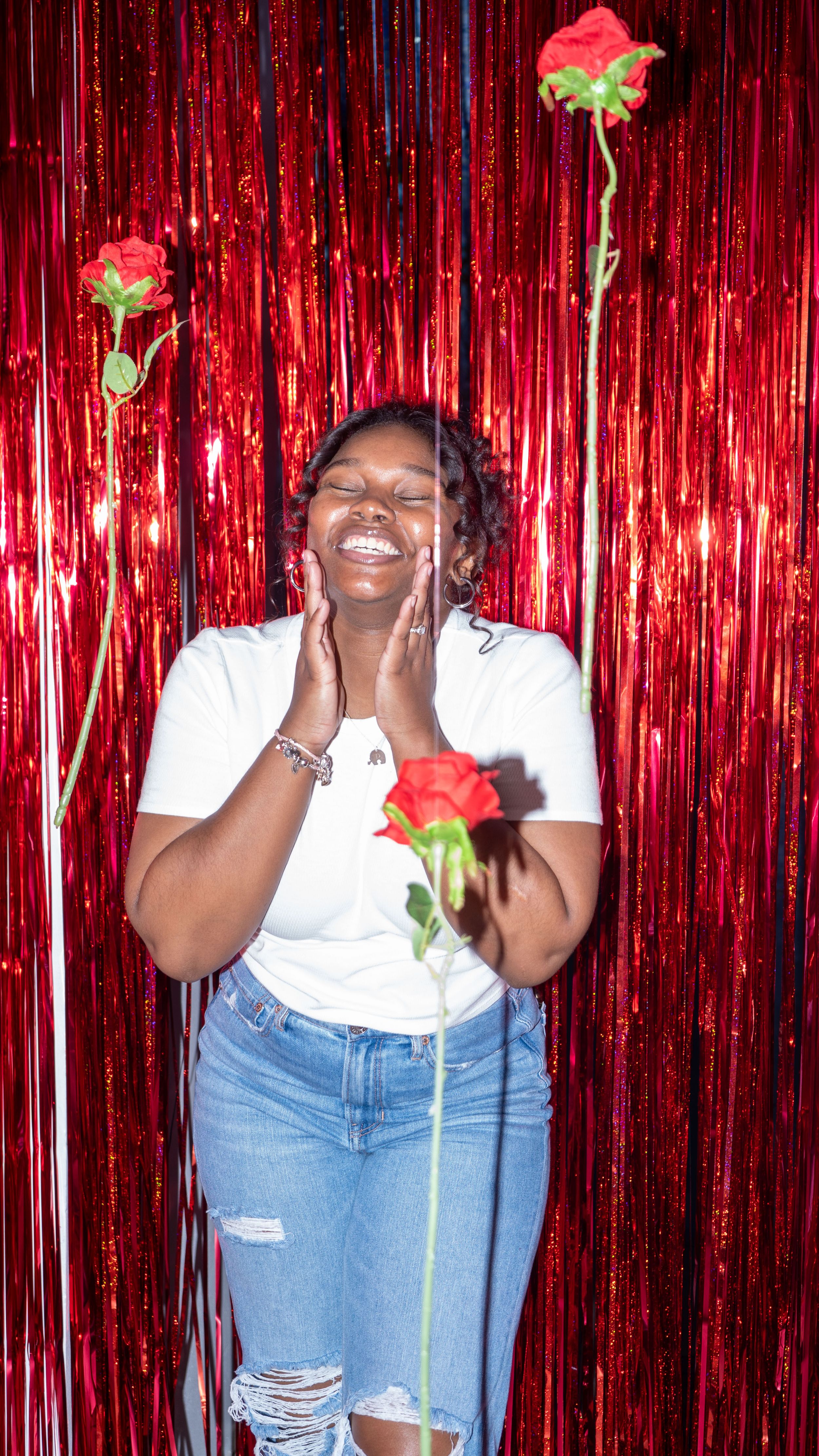 Joyful portrait against red tinsel backdrop with floating roses.