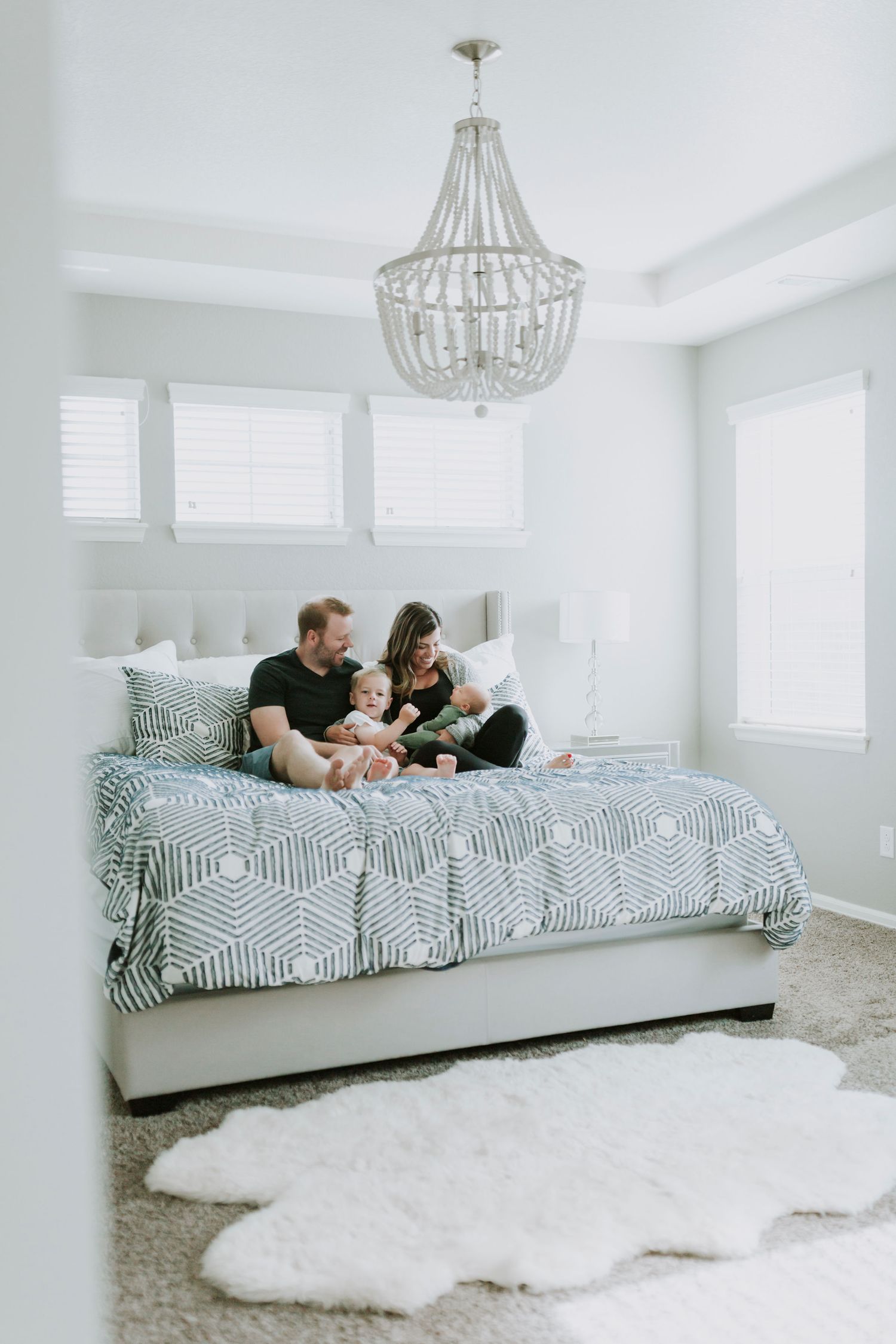 Family sitting in master bedroom on bed holding two young boys