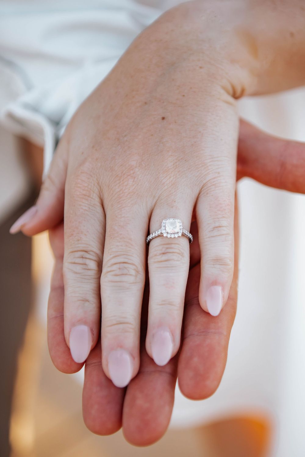 Close-up shots of hands displaying a sparkling engagement ring.