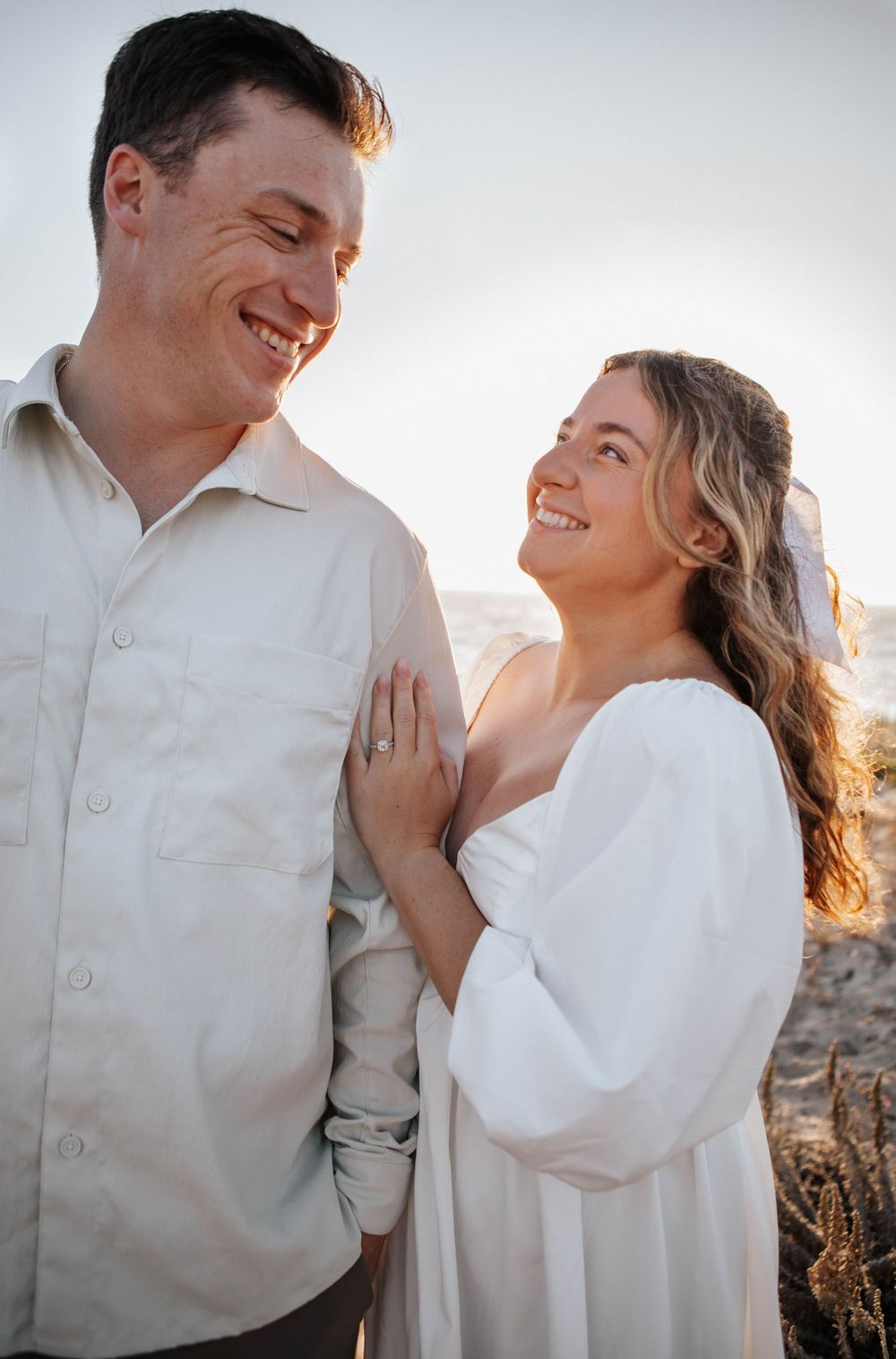A romantic couple embraces and laughs together during a sunset photoshoot.