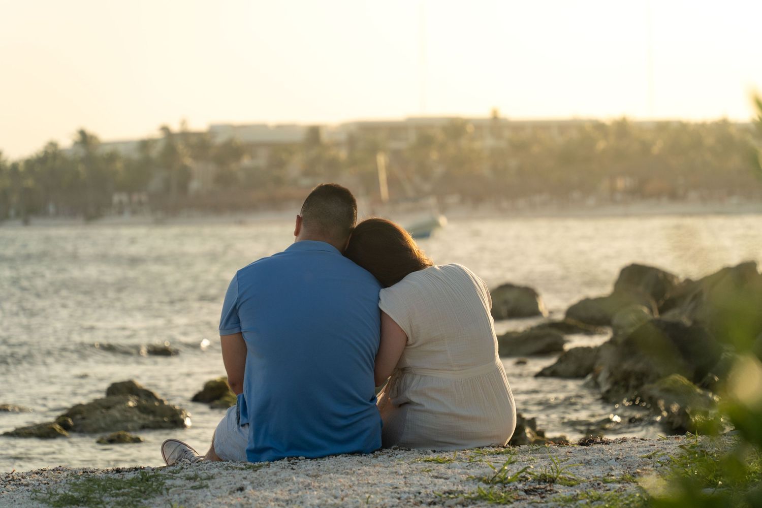 Couples sitting on rocks watching a coastal sunset.