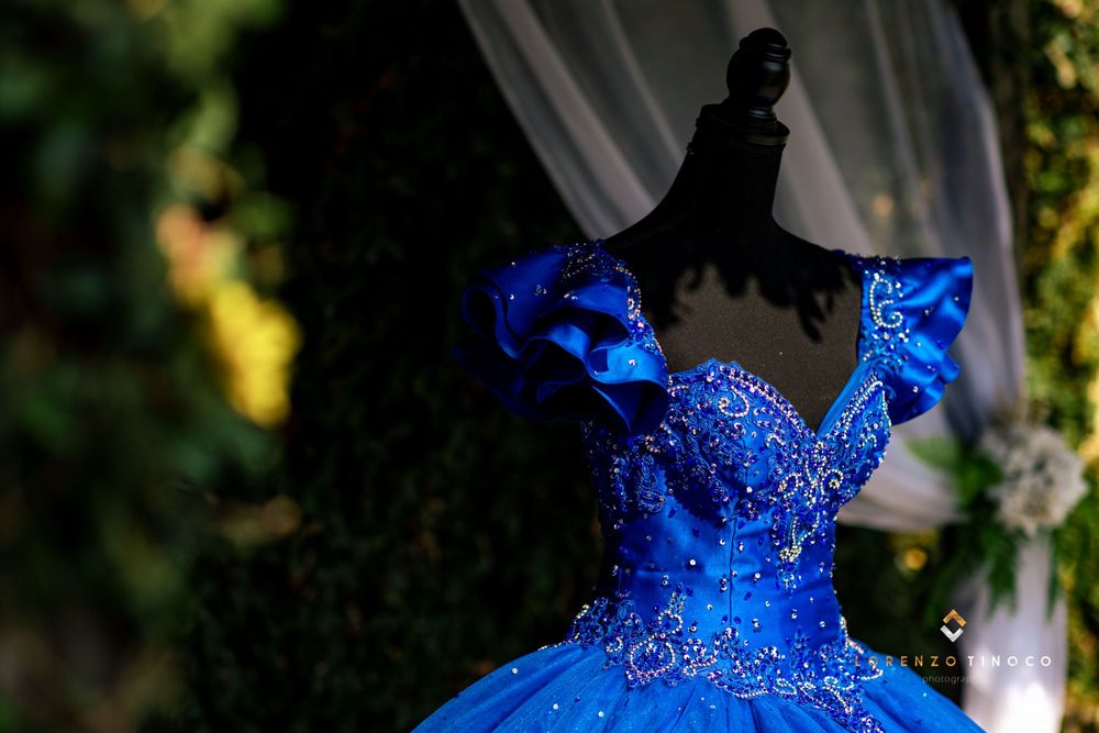 A stunning royal blue quinceañera dress with intricate beading captured in dramatic lighting.