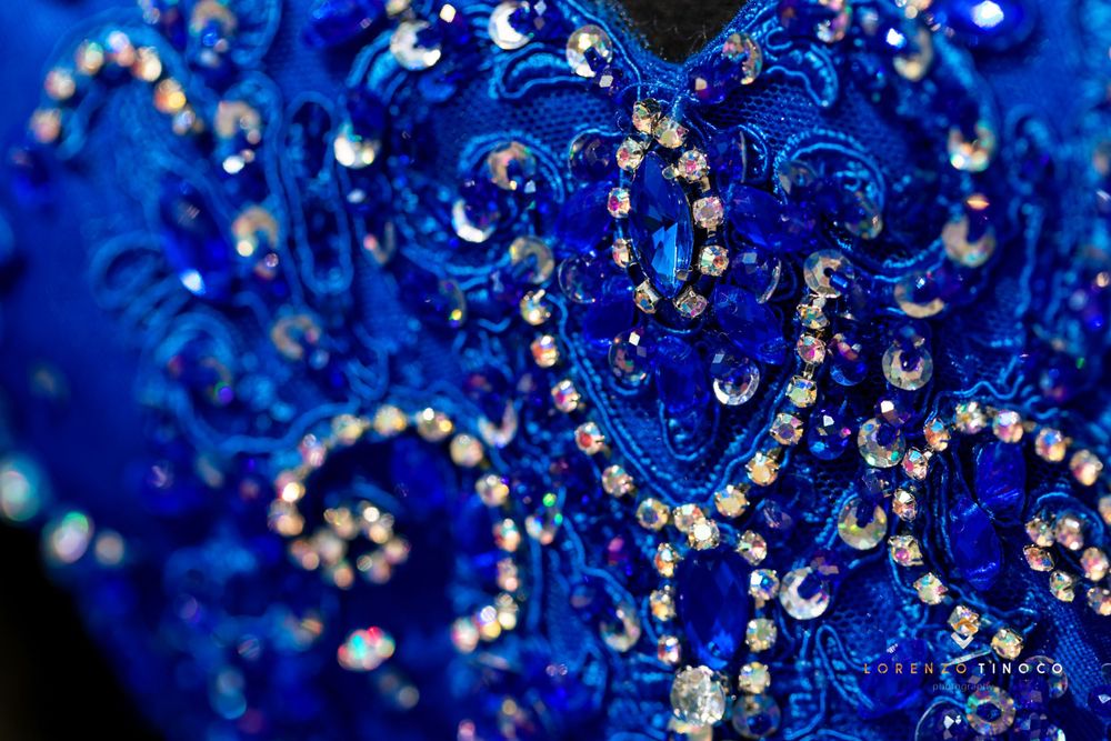Macro shot of intricate crystal beadwork on royal blue fabric with sparkling details.