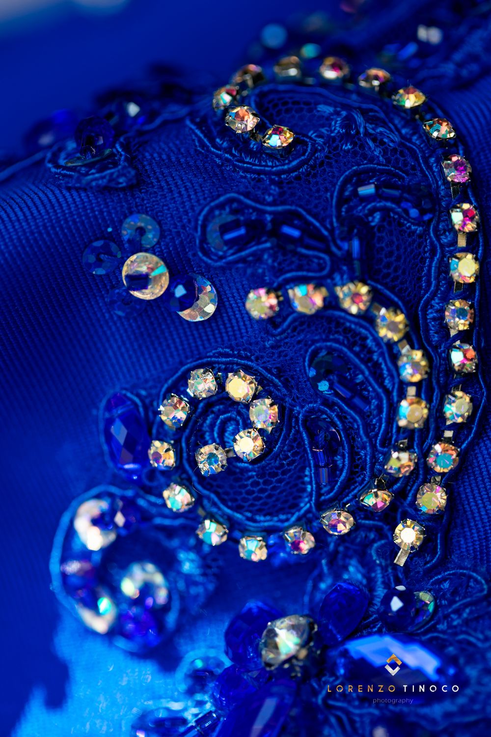 Detailed macro photograph of crystal embellishments on royal blue fabric with intricate patterns.