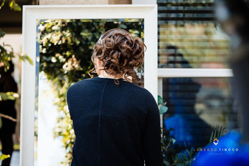 A figure in a navy sweater is shown from behind with an elegant updo hairstyle in natural outdoor lighting.