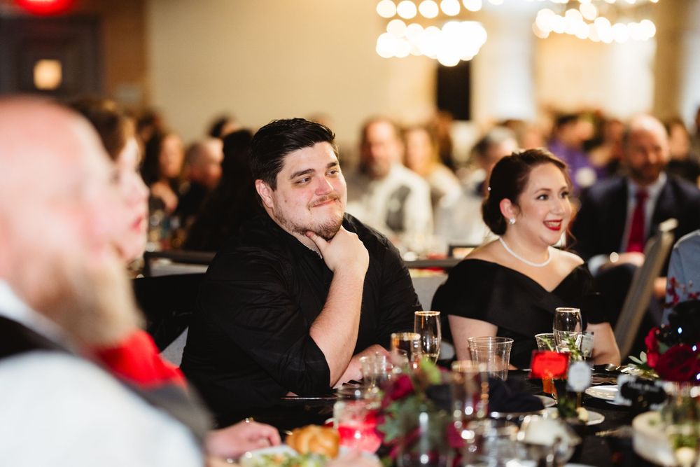 Wedding guests at a table enjoying the reception in a warmly lit banquet hall.